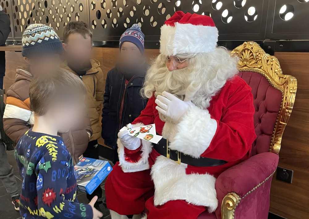 Le Père Noël remettant un cadeau à un enfant lors d'un arbre de Noël d'entreprise