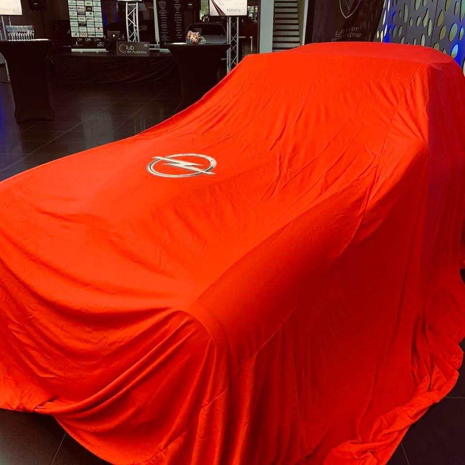 Véhicule sous un drap de dévoilement rouge avant présentation